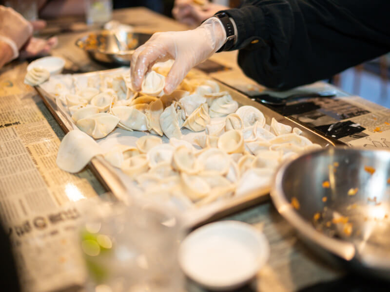 Hand reaching for dumplings on a tray